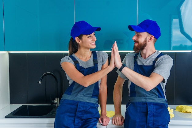 satisfied cleaners blue uniforms giving each other high five continuing clean floor kitchen 141188 2612